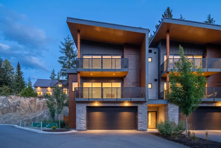 Multi-level contemporary exterior with stone accents, wood paneling, and glass-paneled balconies