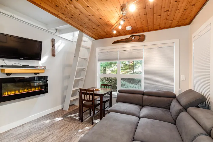 Living area featuring track lighting, wood ceiling, a glass covered fireplace, and light wood-type flooring