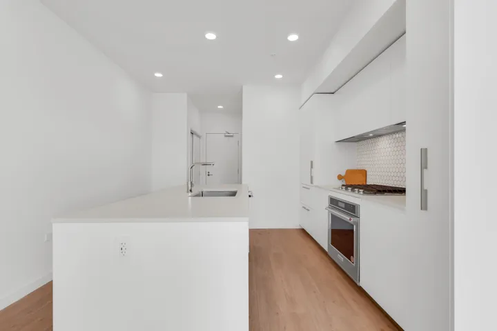 Kitchen featuring stainless steel appliances, white cabinets, modern cabinets, decorative backsplash, and light stone counters