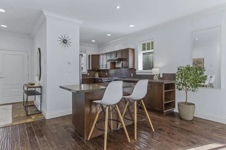 Kitchen featuring dark wood-type flooring, dark wood finish cabinets, tasteful backsplash, crown molding, and a center island