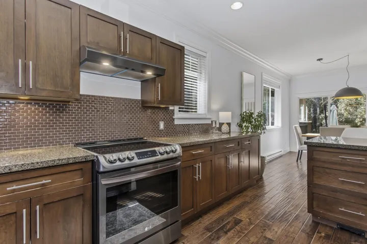 Kitchen with stainless steel range with electric stovetop, crown molding, light stone countertops, dark wood-style flooring, and healthy amount of natural light