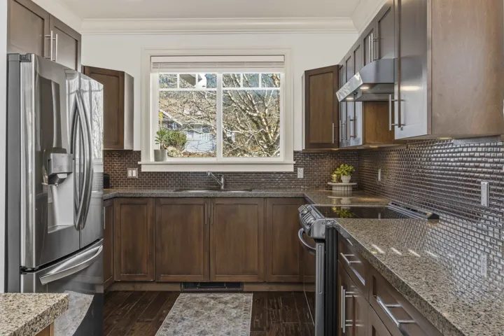 Kitchen featuring stainless steel appliances, dark stone countertops, crown molding, and dark wood-type flooring