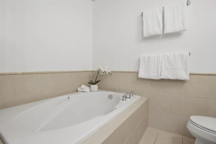 Full bathroom with tile walls, a bath, light tile patterned floors, and a wainscoted wall