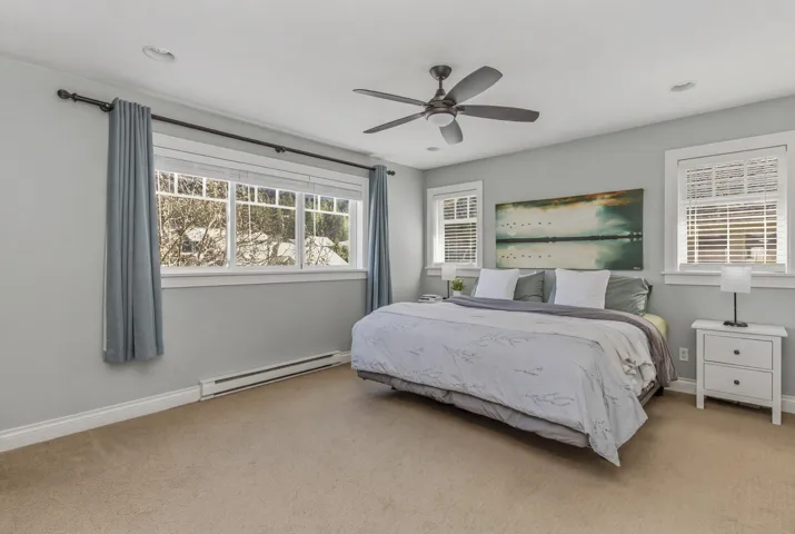 Carpeted bedroom with baseboard heating and ceiling fan