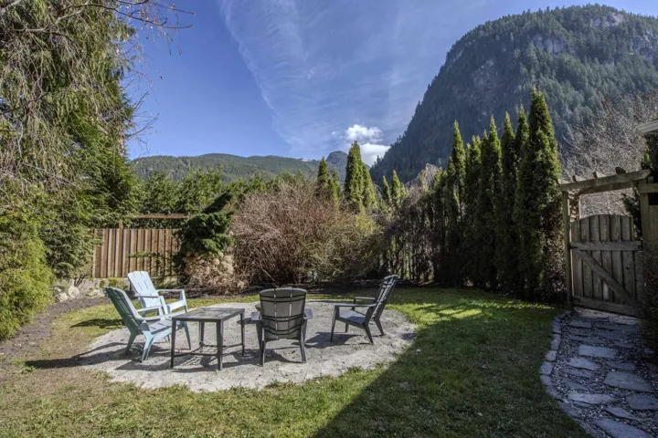 Fenced yard featuring a patio, a mountain view, a fire pit, and a gate