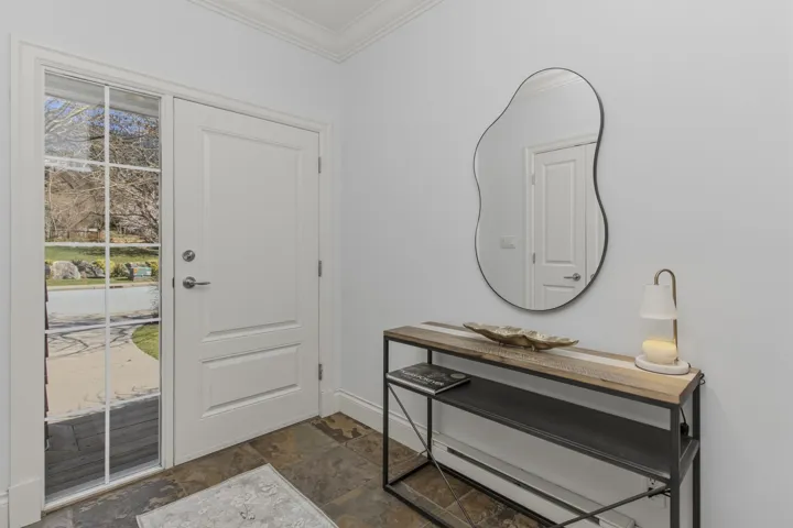 Entryway with dark stone finish floors and ornamental molding