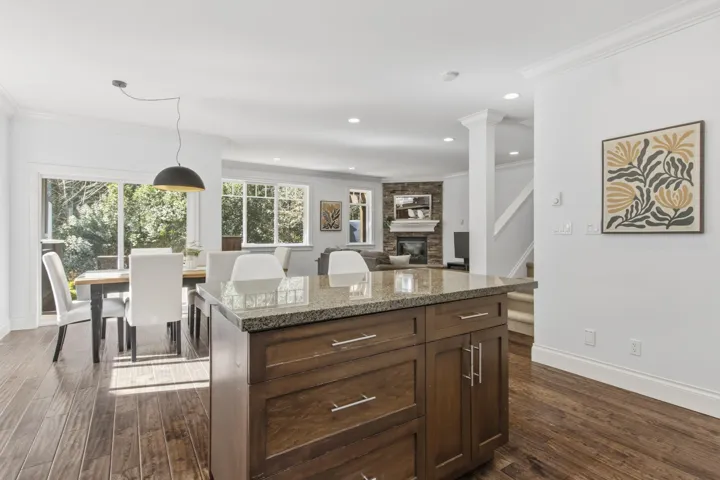 Kitchen with dark wood finish cabinetry, a center island, dark wood-style floors, a fireplace, and ornamental molding