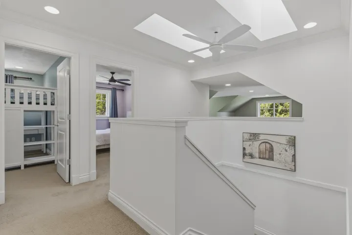 Hall featuring light colored carpet, ornamental molding, an upstairs landing, recessed lighting, and a skylight