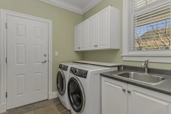 Laundry room with crown molding, separate washer and dryer, cabinet space, and dark stone finish flooring