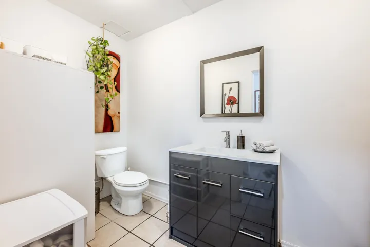 Half bathroom featuring tile flooring, vanity, toilet, and front loading washer/dryer
