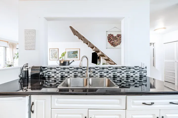 Kitchen with dishwasher, dark countertops, a sink, and white cabinets