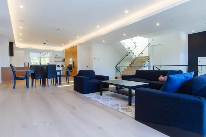 Living room with light wood finished floors, a chandelier, stairway, and recessed lighting