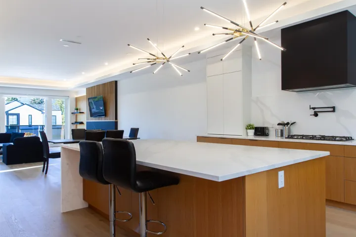 Kitchen featuring modern cabinets, a spacious island, decorative backsplash, a chandelier, and light stone countertops