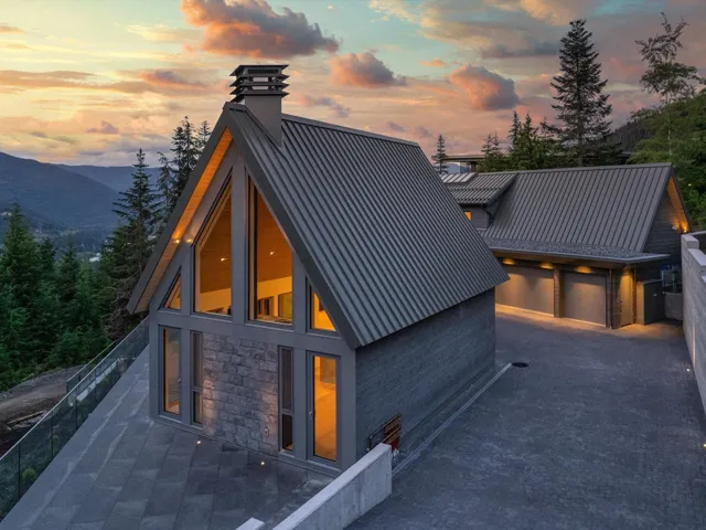 View of front facade featuring stone siding, a chimney, a garage, and a mountain view