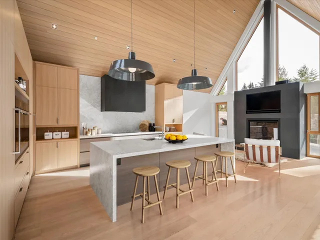 Kitchen featuring light brown cabinetry, modern cabinets, a kitchen bar, wood ceiling, and decorative light fixtures