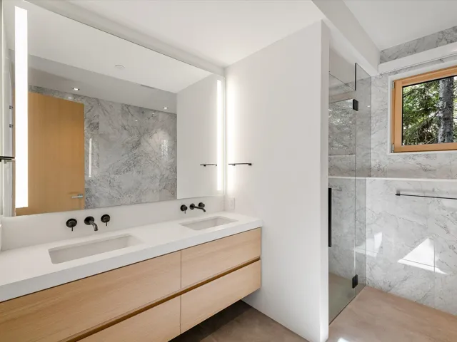 Full bath with double vanity and a marble finish shower