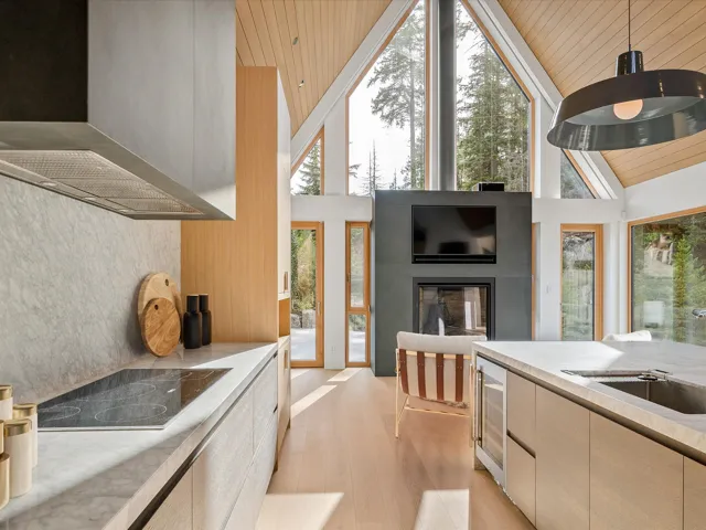 Kitchen featuring wall chimney exhaust hood, light countertops, wooden ceiling, black electric stovetop, and a large fireplace