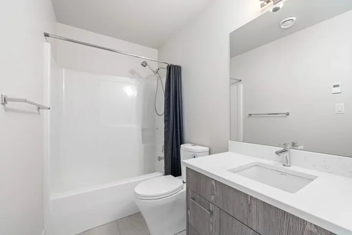Bathroom with toilet, tile patterned floors, shower / bath combo with shower curtain, and vanity