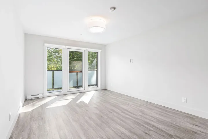 Empty room featuring baseboard heating, a smoke detector, wood finished floors, and baseboards