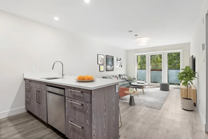 Kitchen featuring a sink, a peninsula, light wood-style floors, light countertops, and dishwasher