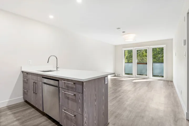 Kitchen with a sink, a peninsula, light wood-style flooring, and baseboards