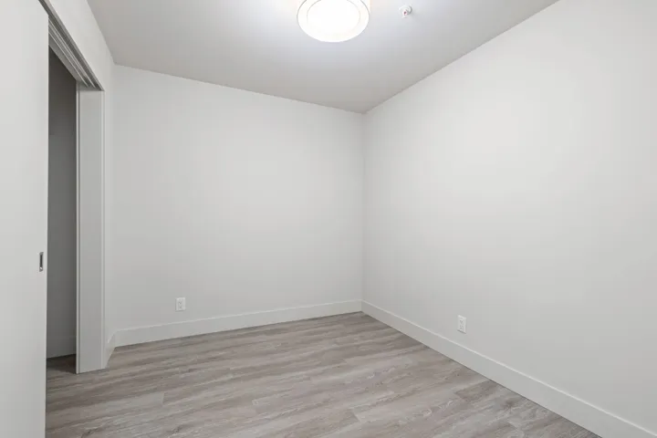 Unfurnished room featuring baseboards, light wood finished floors, and fire sprinkler in ceiling