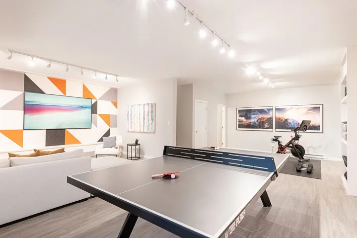 Recreation room with track lighting, light wood-style flooring, and a baseboard radiator