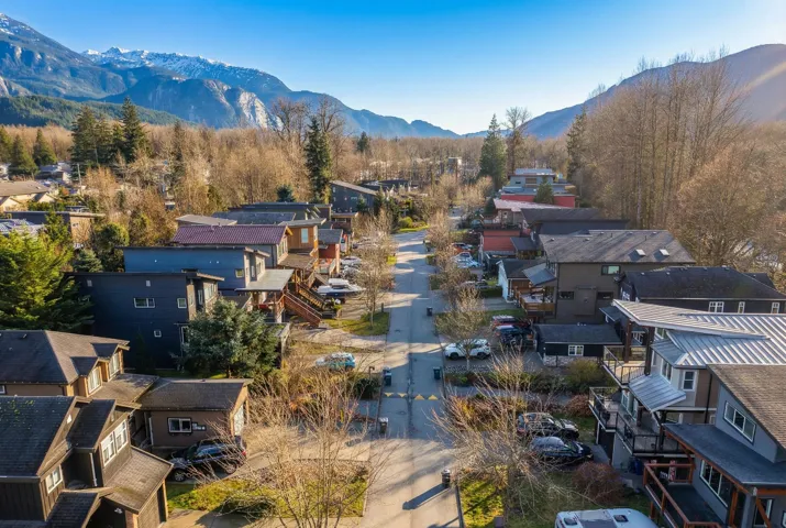 Residential street framed by mountainous terrain and established trees