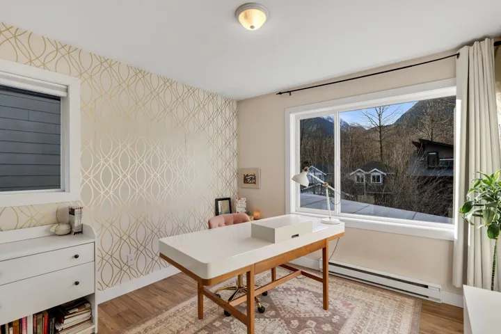 Interior space featuring a large window with mountain scenery, a secondary window, and a wall with a geometric patterned accent wallpaper
