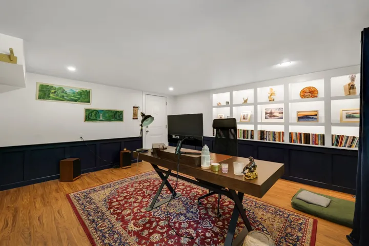 Recessed shelving with integrated lighting, wood-finish flooring, and white walls with dark wainscoting
