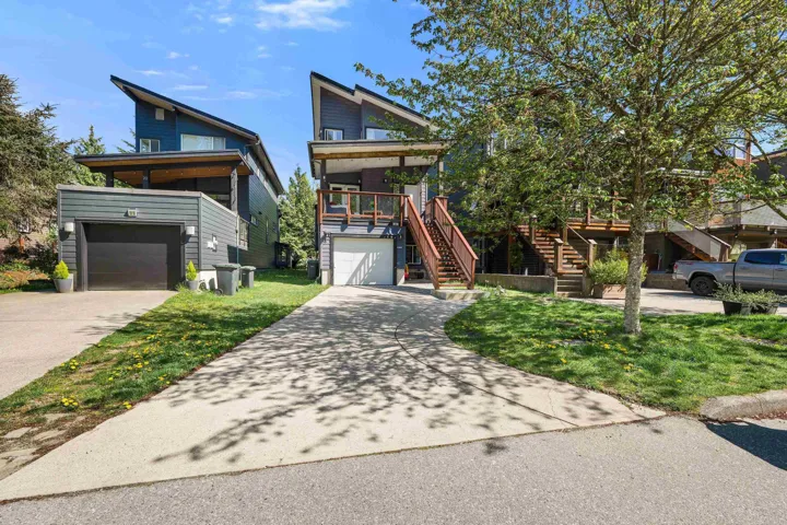 Contemporary exterior featuring a distinctive sloped roofline, attached garage with a dark door, and a covered balcony