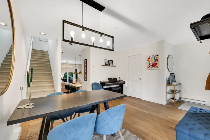 Open-concept dining area featuring wood-finish flooring, a contemporary linear chandelier, and a built-in staircase with carpeted treads
