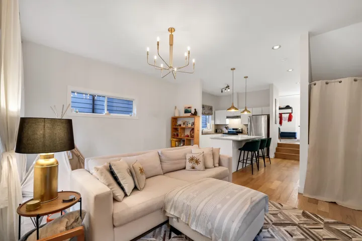 Open-concept living space featuring wood-finish flooring, recessed lighting, and a modern chandelier