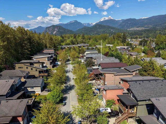 Residential street featuring a variety of architectural styles, mature trees, and a distant mountain range with snow-capped peaks
