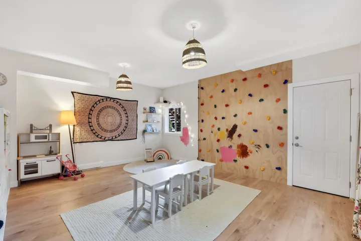 Spacious room featuring light wood-finish flooring, recessed lighting, and two woven pendant light fixtures