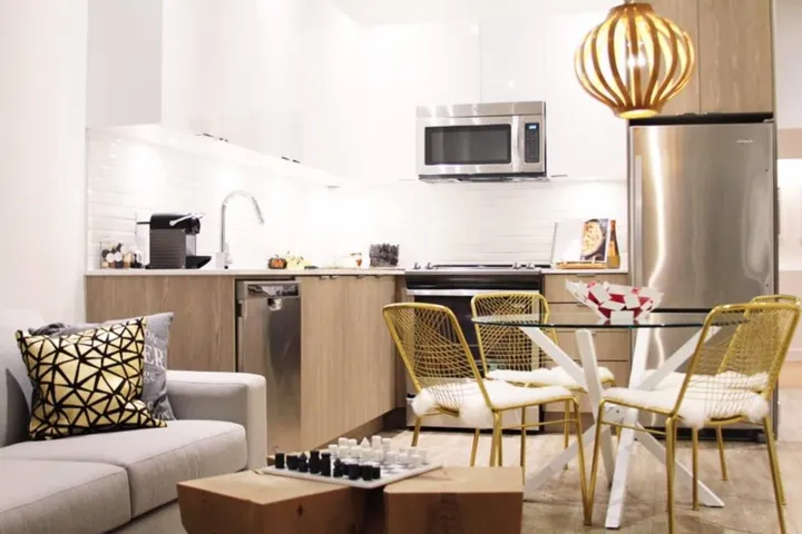 Kitchen featuring modern cabinets, stainless steel appliances, decorative backsplash, light countertops, and white cabinetry