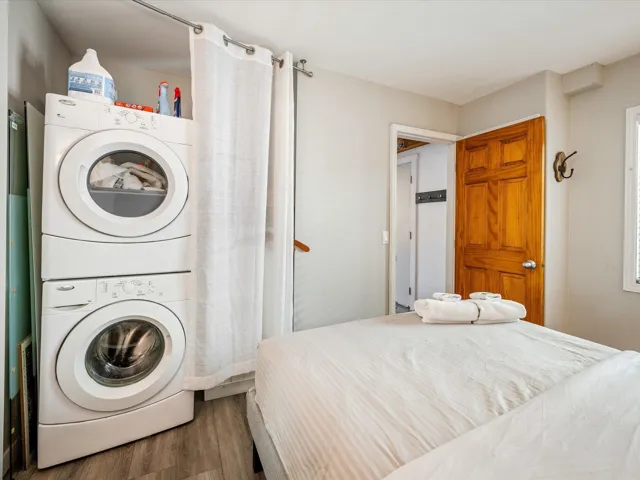Washroom featuring stacked washer / dryer and wood finished floors