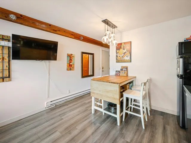 Dining area with a baseboard heating unit, wood finished floors, and baseboards