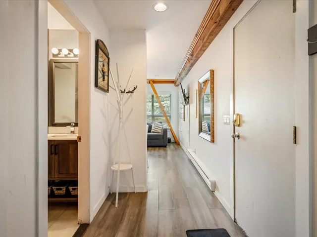 Hall featuring baseboard heating, wood finished floors, baseboards, a sink, and recessed lighting