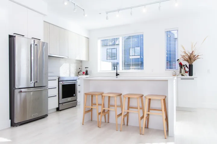 Kitchen with a breakfast bar, stainless steel appliances, light countertops, white cabinets, and modern cabinets