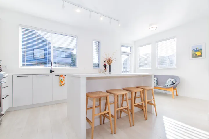 Kitchen with light wood finished floors, a kitchen island, a breakfast bar area, light countertops, and white cabinetry