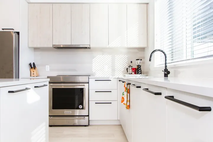 Kitchen with modern cabinets, stainless steel appliances, light countertops, under cabinet range hood, and a sink
