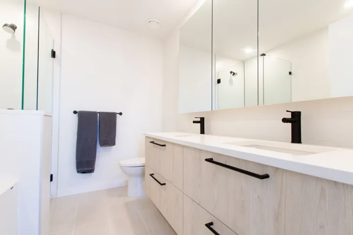 Bathroom with double vanity, a stall shower, toilet, tile patterned floors, and a sink