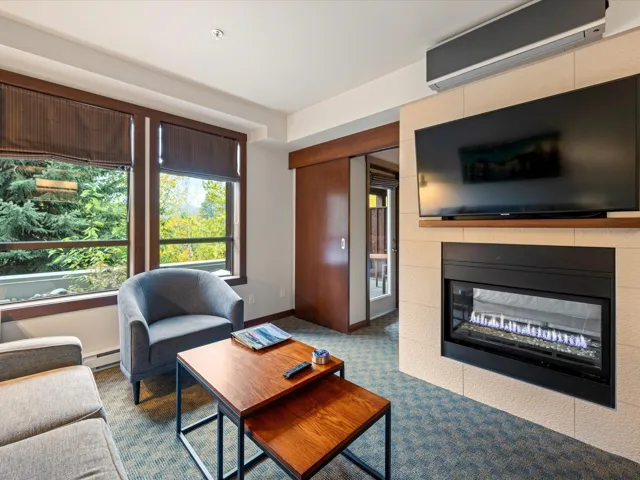 Living area with a tile fireplace, carpet flooring, a wall unit AC, and a baseboard heating unit