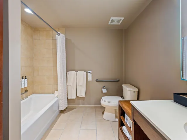 Bathroom featuring light tile patterned flooring, vanity, and shower / tub combo