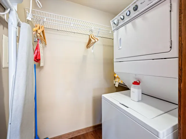 Washroom with estacked washer and dryer and dark wood-style floors
