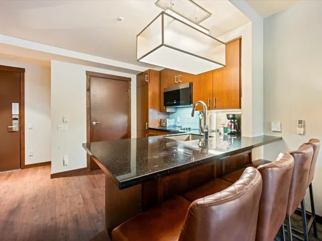Kitchen with tasteful backsplash, brown cabinetry, a kitchen bar, dark wood-style floors, and a peninsula