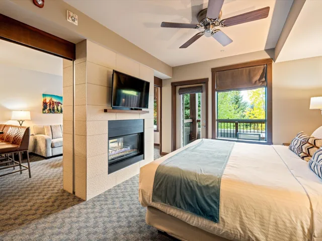 Carpeted bedroom with access to exterior, a tiled fireplace, and ceiling fan