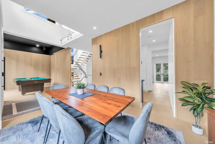 Open-concept dining area featuring light wood-finish flooring, a light wood paneled accent wall, and recessed lighting