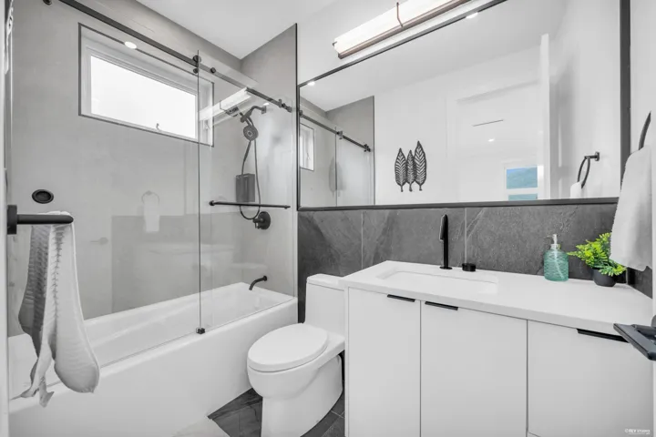 Contemporary bathroom featuring a tub-shower combination with a sliding glass door and a rectangular window